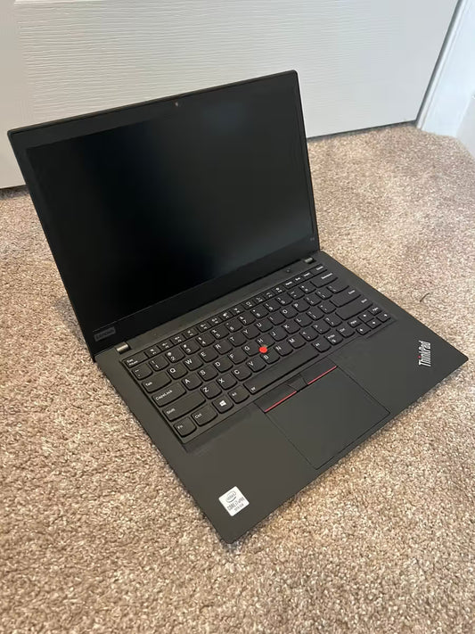 Black laptop on a carpeted floor with a neutral background